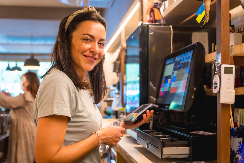 A waitress smiling while at the cash registry